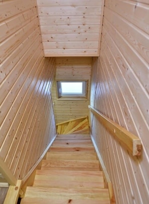 A wooden staircase leading to a skylight.