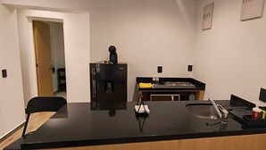 A kitchen with a black countertop, a coffee machine, a sink, and a refrigerator. - Sevillavenue (Ciudad de México)