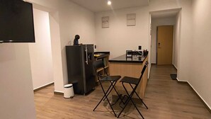 A modern kitchen with a refrigerator, a coffee machine, and a dining area with a table and chairs. - Sevillavenue (Ciudad de México)