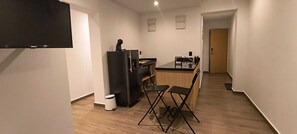Eine moderne Küche mit Kühlschrank, einer Kaffeemaschine und einem Essbereich mit Tisch und Stühlen.