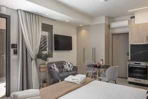 Quarto de hotel moderno com cama, sofá, mesa de jantar e televisão.