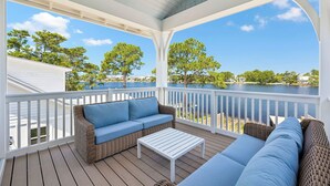 A covered deck with a sofa and a table, overlooking a body of water and trees. - NEW on Eastern Lake.Private pool,hot tub & dock to fish.Walk/SUP to Beach 400yds (Santa Rosa Beach)