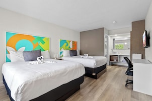 Habitación de hotel con dos camas, un escritorio, una silla y un televisor.