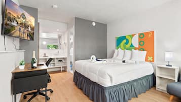 Une chambre d’hôtel équipée d’un lit, d’un bureau, d’une chaise, d’une télévision et d’œuvres d’art.