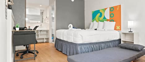 A modern hotel room with a bed, desk, and bench.
