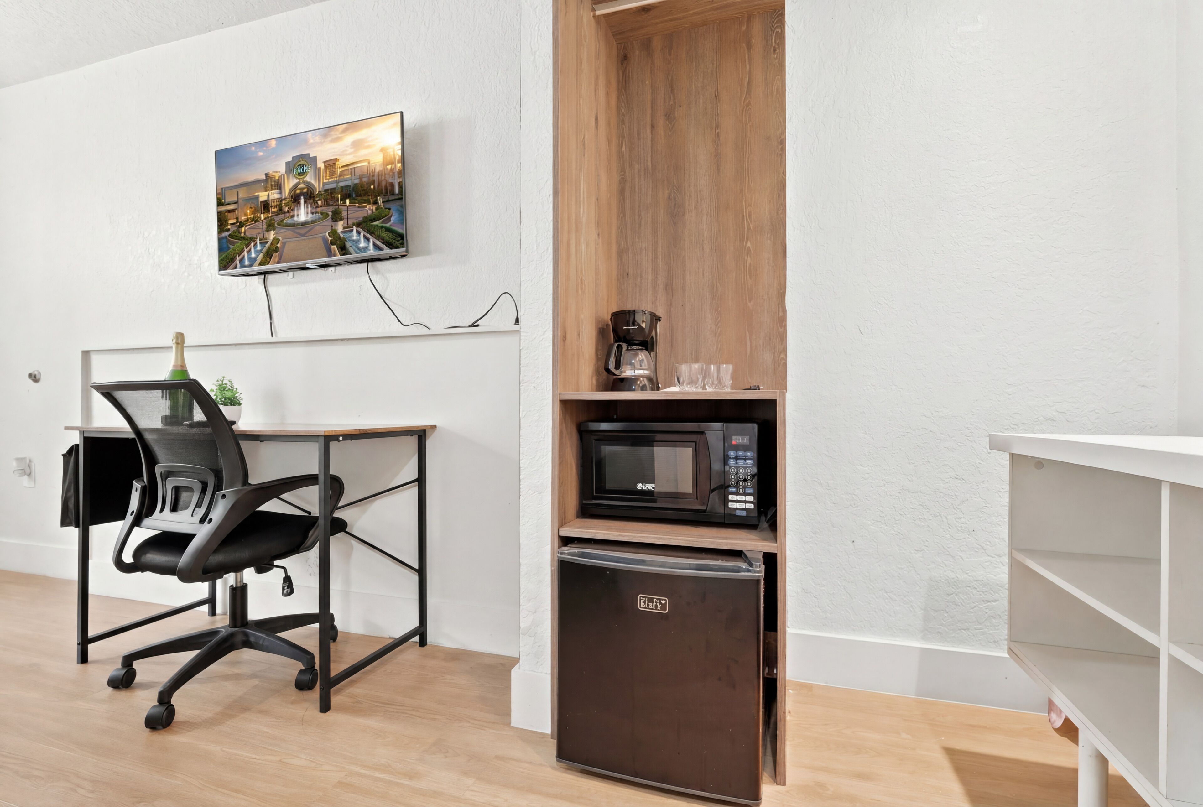 A modern room with a desk, office chair, microwave, and refrigerator.