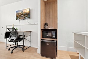 A modern room with a desk, office chair, microwave, and refrigerator. - Budget Disney Room Pool & Parking (Kissimmee)