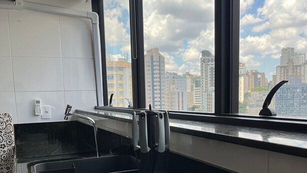 Una cocina con estufa integrada, una ventana con vista a la ciudad y un calentador de agua.