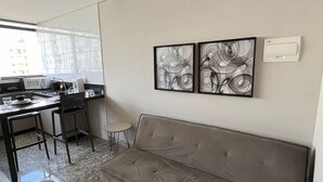 Una sala moderna con un sofá, comedor y una obra de arte en la pared.