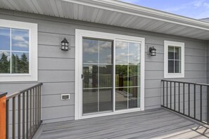 A residential building with a covered porch, sliding glass doors, and two wall-mounted lanterns.