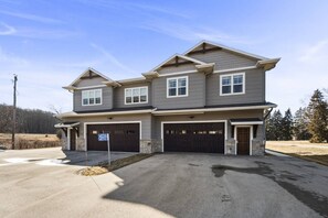 A two-story house with a garage, a driveway, and a clear sky.
