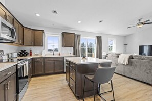 A modern kitchen with dark wooden cabinets, a central island, and a dining area.