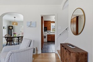 Una habitación con una cama, una mesa de comedor con sillas, una cocina al fondo y un espejo en la pared.