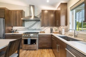 Una cocina moderna con armarios de madera oscura, una estufa de acero inoxidable y un ventanal con vistas al exterior.
