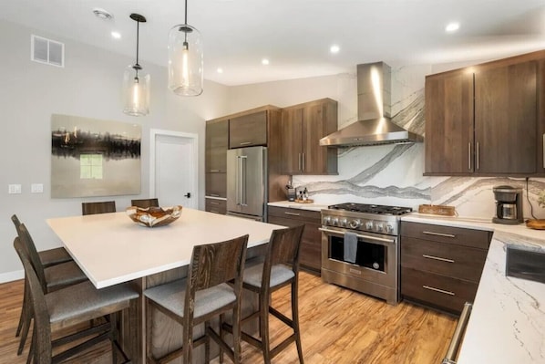 A modern kitchen with a central island, stainless steel appliances, and wooden cabinetry.