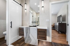 A modern bathroom with a marble vanity, a toilet, and a shower area.