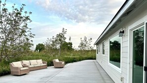 A patio with two wicker sofas and a concrete floor. - HandyFarms.com: California Organic Farm Stay on a Red Walnut Orchard Nut Store (Corning)