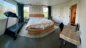 A bedroom with a bed, treadmill, desk, and a view of the outdoors. - HandyFarms.com: California Organic Farm Stay on a Red Walnut Orchard Nut Store (Corning)