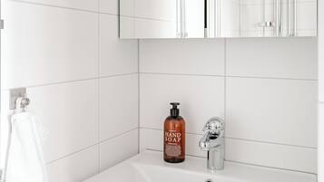 A bathroom with a white sink, a mirror, a handheld soap dispenser, and a towel rack.