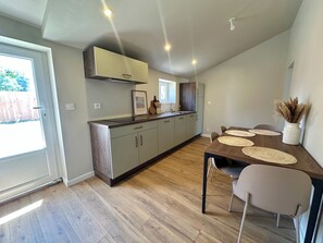 Una cocina moderna con comedor, piso de madera y vista al exterior.