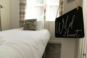 Un dormitorio con una cama, un almohadón y un cartel que dice 'Wild at heart'.