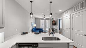 A modern kitchen with a central island, double sinks, and pendant lighting. - New Modern King bed+Pool+Gym+Parking+Stockyards (Fort Worth)