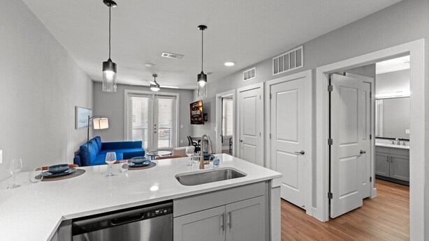 A modern kitchen with a central island, built-in appliances, and pendant lighting. - New Modern King bed+Pool+Gym+Parking+Stockyards (Fort Worth)