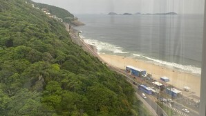 A coastal road with a beach, a highway, and a forested hillside. - Private room at Hotel Nacional, Rio de Janeiro, Brazil (Rio de Janeiro)