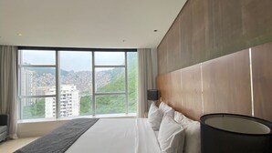 A hotel room with a large bed, a desk, a lamp, and a view of a cityscape. - Private room at Hotel Nacional, Rio de Janeiro, Brazil (Rio de Janeiro)