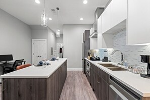Een moderne keuken met een centraal eiland, inbouwapparatuur en hanglampen.
