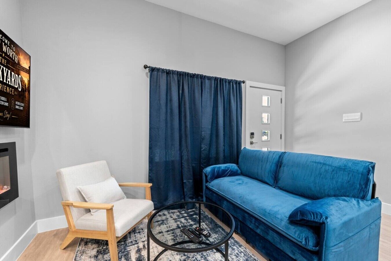 Un salon avec un fauteuil blanc, un canapé bleu, une table basse ronde et une cheminée.