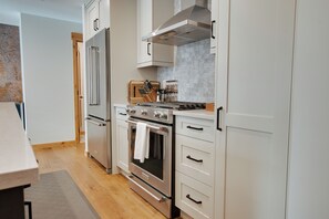 Une cuisine moderne dotée d’appareils électroménagers en acier inoxydable, de plans de travail en bois et de meubles blancs.