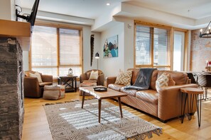 Ein Wohnzimmer mit braunem Ledersofa, einem Holztisch und einem gemusterten Teppich.