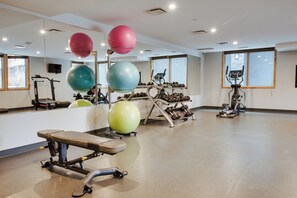 Une salle de sport équipée de matériel d’exercice, d’un banc et de grands ballons d’exercice.