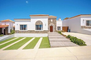 Une maison moderne avec une façade en pierre, un toit en tuiles et une pelouse bien entretenue.
