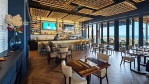 Uma área de bar com televisão, assentos e vista para o oceano.