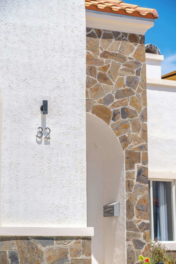 Un bĂątiment dotĂ© dâune façade en pierre, dâun mur blanc ornĂ© dâun numĂ©ro et dâune fenĂȘtre avec un rideau.