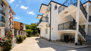 Un immeuble résidentiel doté de balcons, d’une allée pavée et d’un vélo garé à l’extérieur.