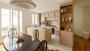 Una cocina moderna con una isla central, electrodomésticos integrados y un comedor con una mesa redonda y sillas.