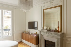 Ein Zimmer mit Kamin, einem an der Wand befestigten Fernseher und einem Fenster mit Balkonblick.