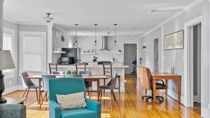 A spacious living room with a teal armchair, a dining area with a wooden table and chairs, and a kitchen with white subway tiles and stainless steel appliances. - Hearthside Haven | Avondale/Fenced Yard/King Bed (Birmingham)