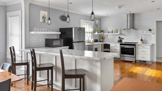 A modern kitchen with white cabinetry, a marble island, and pendant lighting. - Hearthside Haven | Avondale/Fenced Yard/King Bed (Birmingham)