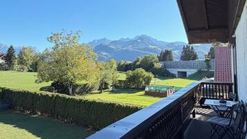 A balcony with a view of a green landscape and mountains in the distance.