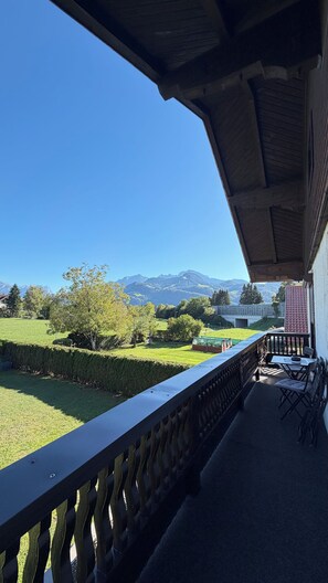 Un balcon donnant sur un paysage verdoyant et sur des montagnes à l’horizon.