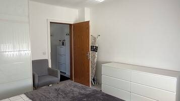 A bedroom with a bed, a wardrobe, a desk, and a door leading to another room.