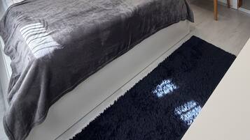 Een moderne slaapkamer met een groot bed, een stoel, een spiegel en een kledingkast.