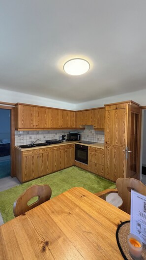 Une cuisine moderne avec des meubles en bois, un four à micro-ondes et un four encastré.
