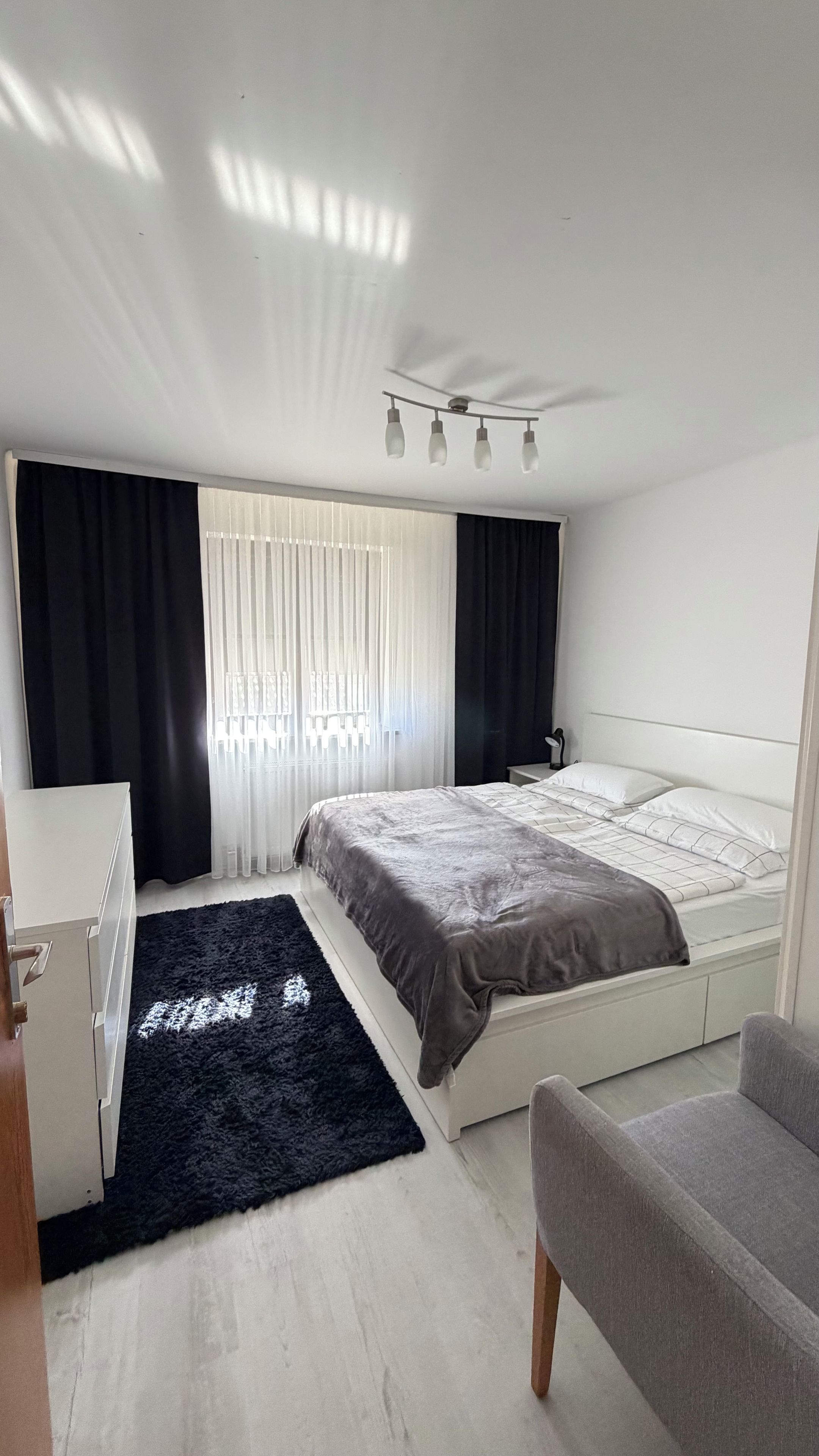 A modern bedroom with two beds, a desk, and a chair.