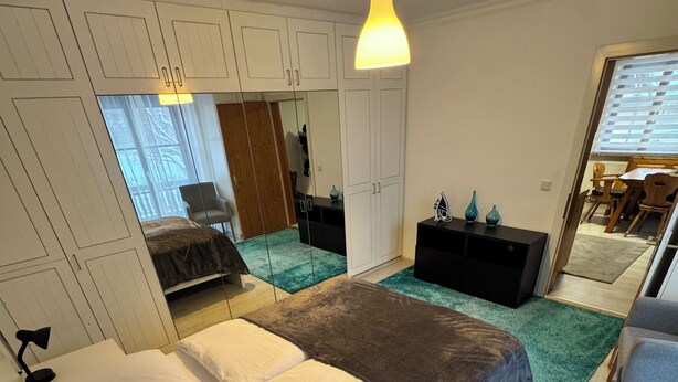 Une chambre à coucher comprenant un lit, une commode, un miroir et un luminaire au plafond.