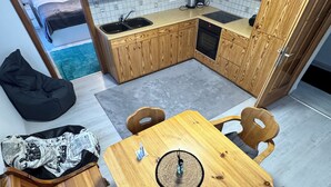 Une cuisine compacte avec des meubles en bois, une petite table à manger et un fauteuil en forme de sac de haricots.